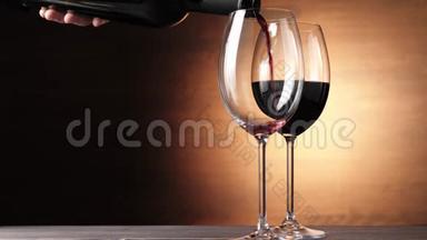 豪华红酒。 手从瓶子里倒出美味的葡萄酒，在靠近第二杯的棕色背景下。 玫瑰酒